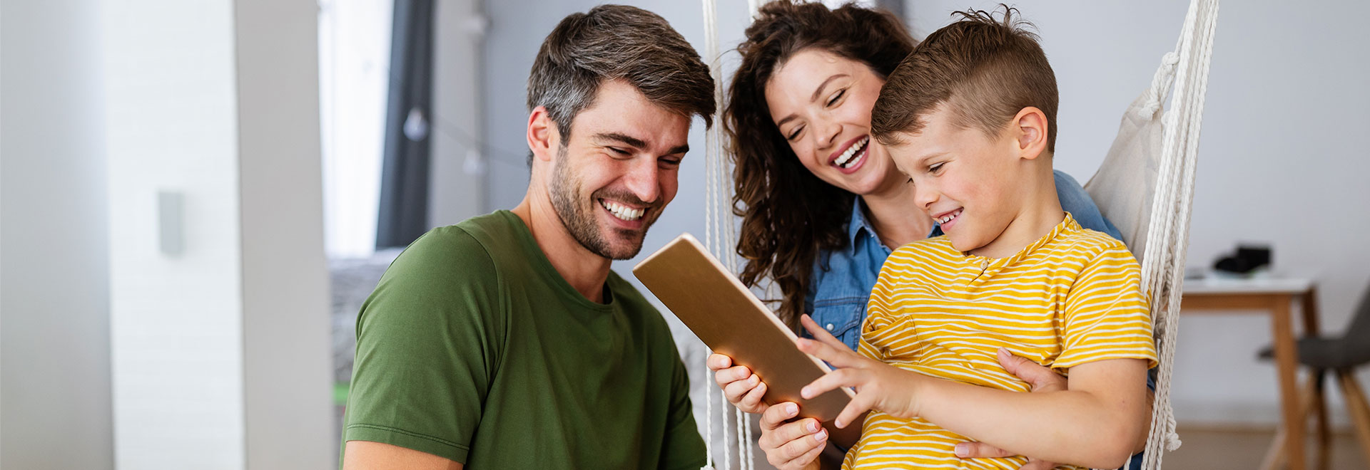 Vater, Mutter und Kind schauen gemeinsam auf ein Tablet