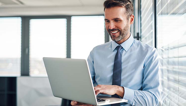 Geschäftsmann steht mit einem Laptop im Büro