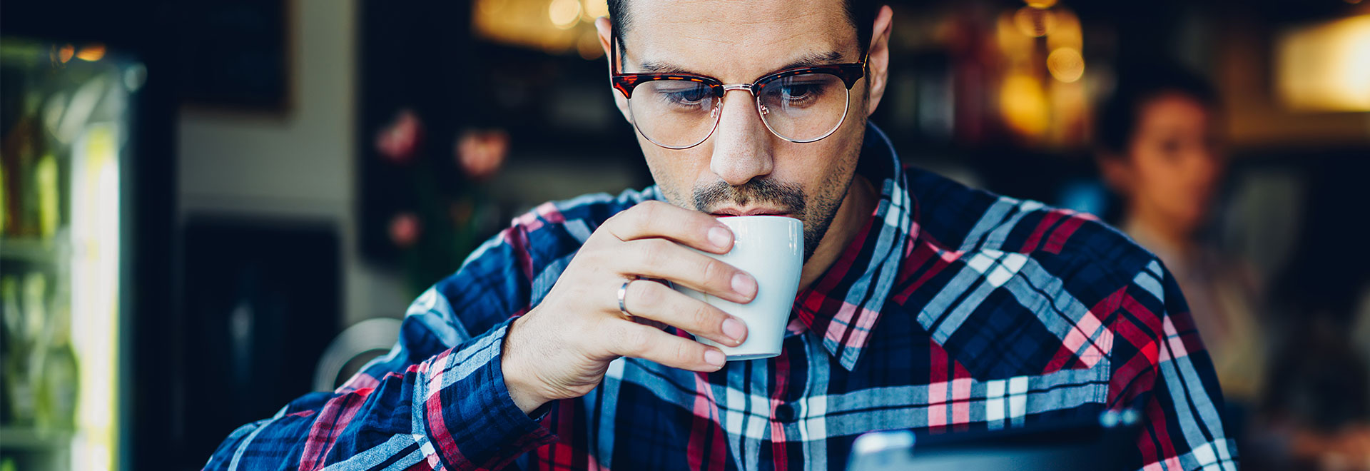 Mann trinkt Kaffee und sieht auf sein Tablet