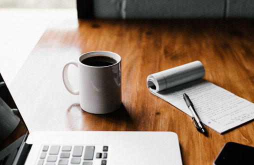Das richtige Klimatisierungskonzept kann ein wichtiger Kostenfaktor sein Kaffeetasse auf einem Tisch mit Laptop und Block