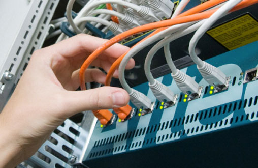 Systemtechniker kümmern sich um die Hardware im Rechenzentrum Hand steckt LAN-Kabel in einen Server