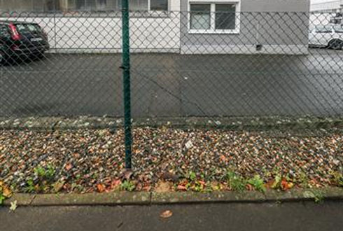 Ihr Gebäude vor den Baumaßnahmen Ansicht einer Gewerbeimmobilie mit Parkplatz und Zaun im Vordergrund