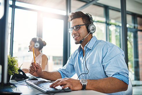 Leistungsstarke Internetanbindung für Ihr Unternehmen Mann mit Headset sitzt in einem Großraumbüro vor einem Computer
