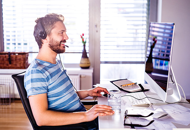 Mann arbeitet mit Headset im Home Office