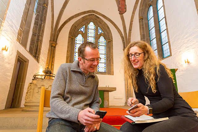 Mitarbeiter der Georgs-Kirchengemeinde in der Kirche mit einem Telefon