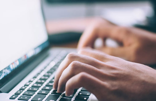 Hände schreiben auf einer Tastatur