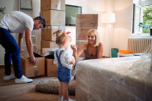 Umzug in eine multimediale Wohnung Fröhliche Familie packt Umzugskisten