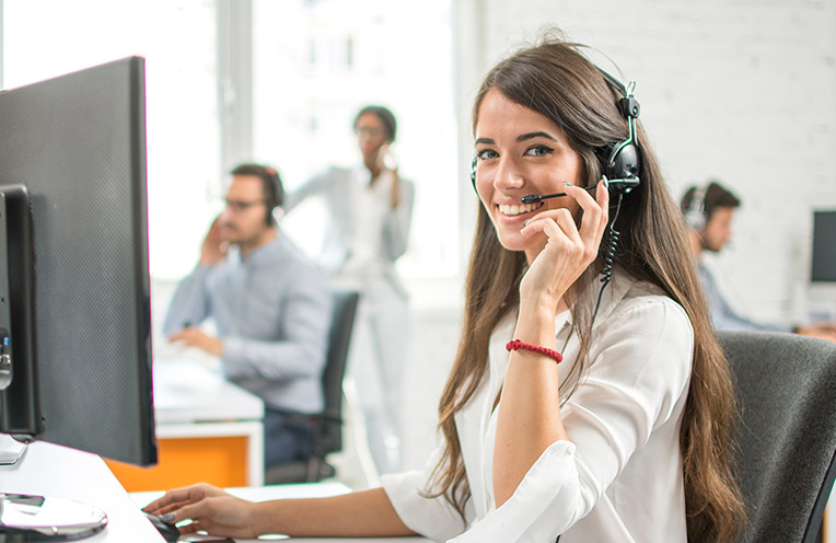 Frau mit Headset sitzt vor einem Computer