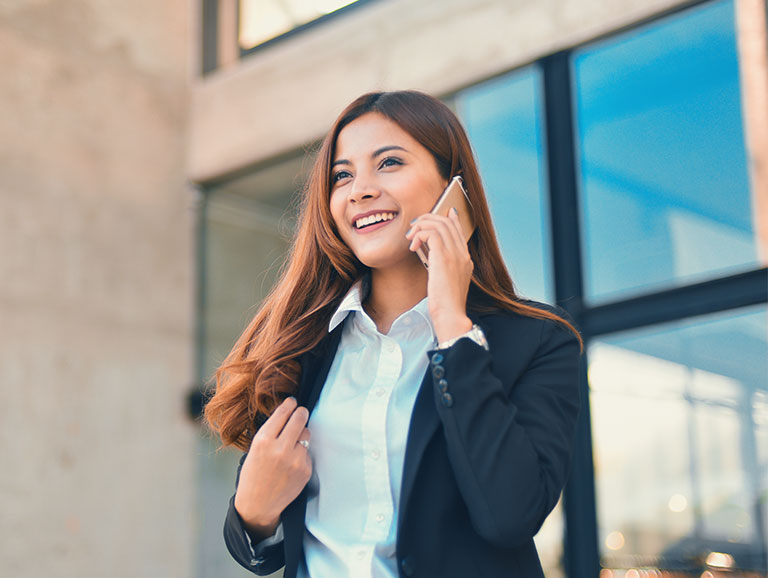 Frau telefoniert mit ihrem Smartphone vor einem Bürogebäude