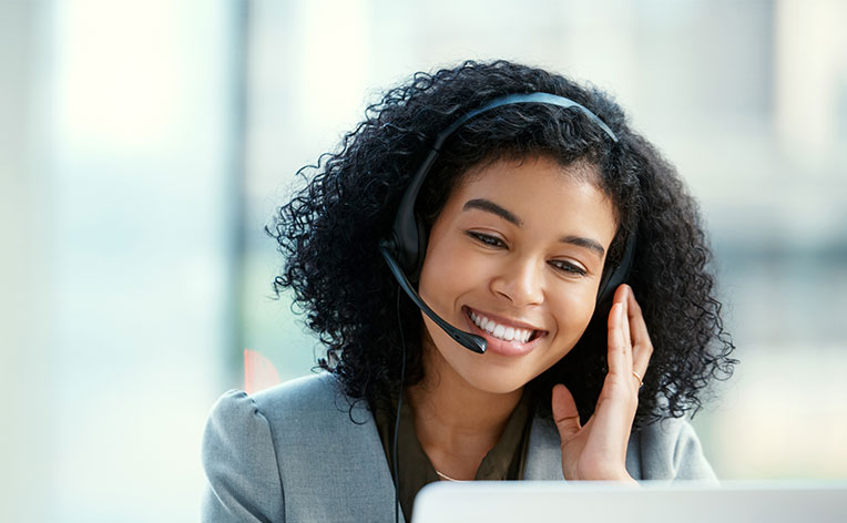 Junge Frau mit Headset sitzt vor einem Laptop