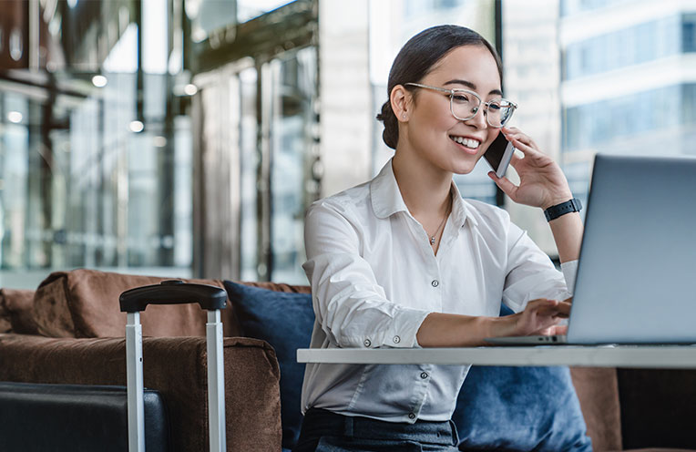Frau sitzt telefonierend vor einem Laptop