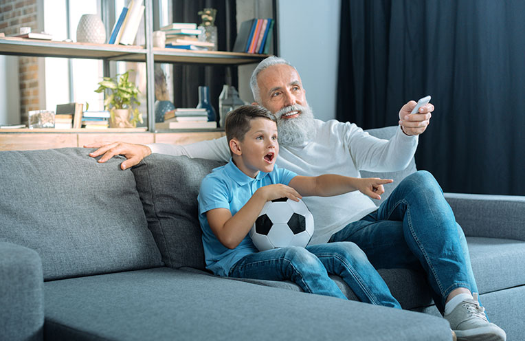 Großvater und Enkel sitzen auf der Couch und schauen Fußball
