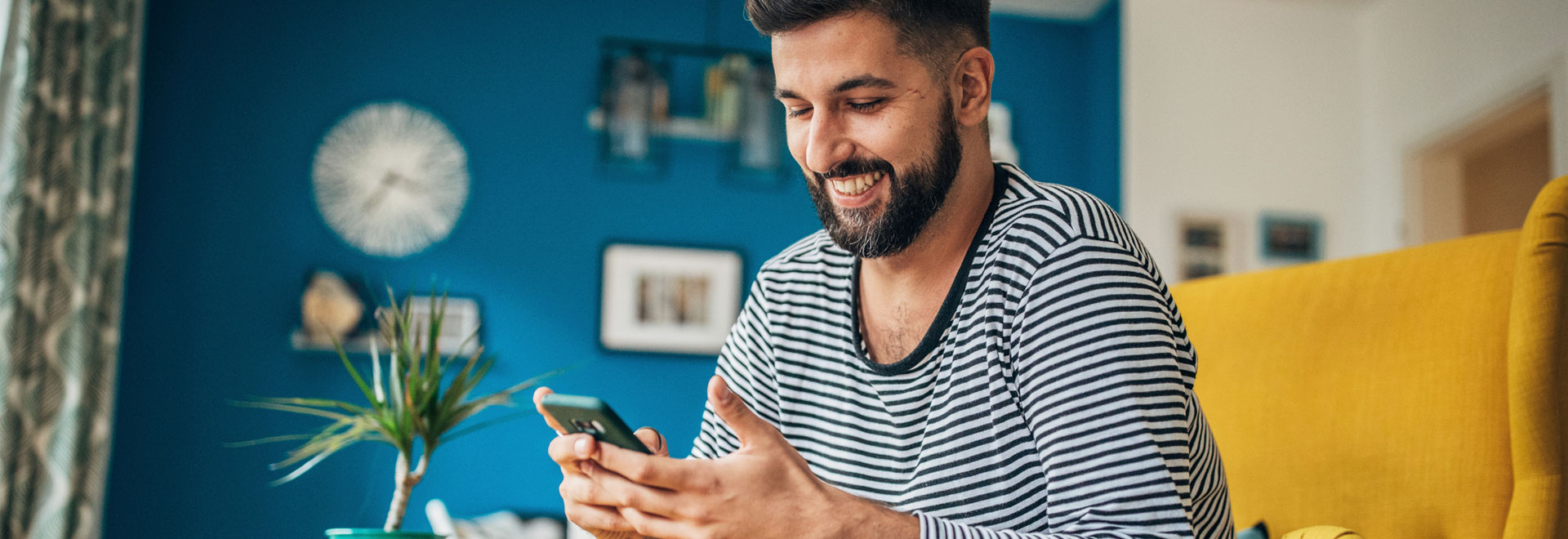 Junger Mann schaut lachend auf sein Smartphone