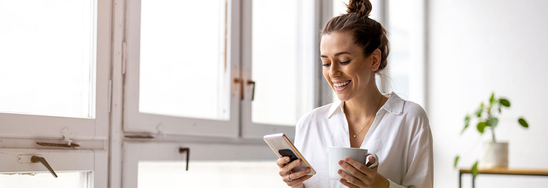 Frau schaut lächelnd auf ihr Smartphone