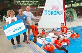DOKOM21 Mitarbeiterin im Schwimmbad mit Kindern und Betreuern in und an einem DOKOM21 Segelboot