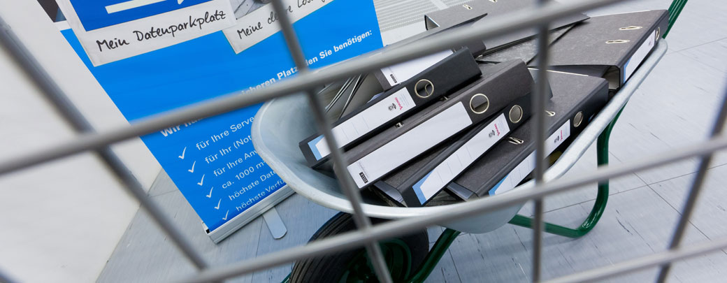 Im DOKOM21 Rechenzentrum stehen individuelle Flächenkonzepte zur Verfügung Aktenordner auf einer Schubkarre hinter einem Gitter